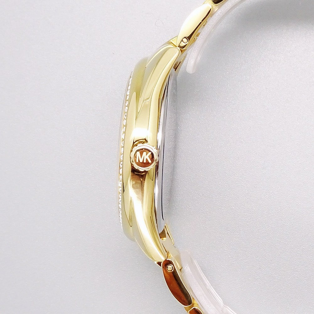 Side view of Michael Kors MK7090 watch showing gold-tone case with crystal bezel and metal strap