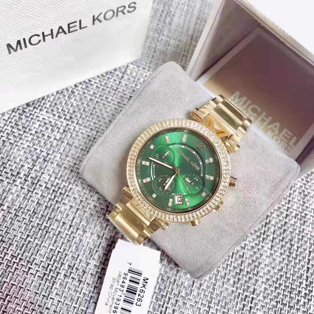 Michael Kors Parker watch with gold bracelet displayed on branded pillow in packaging