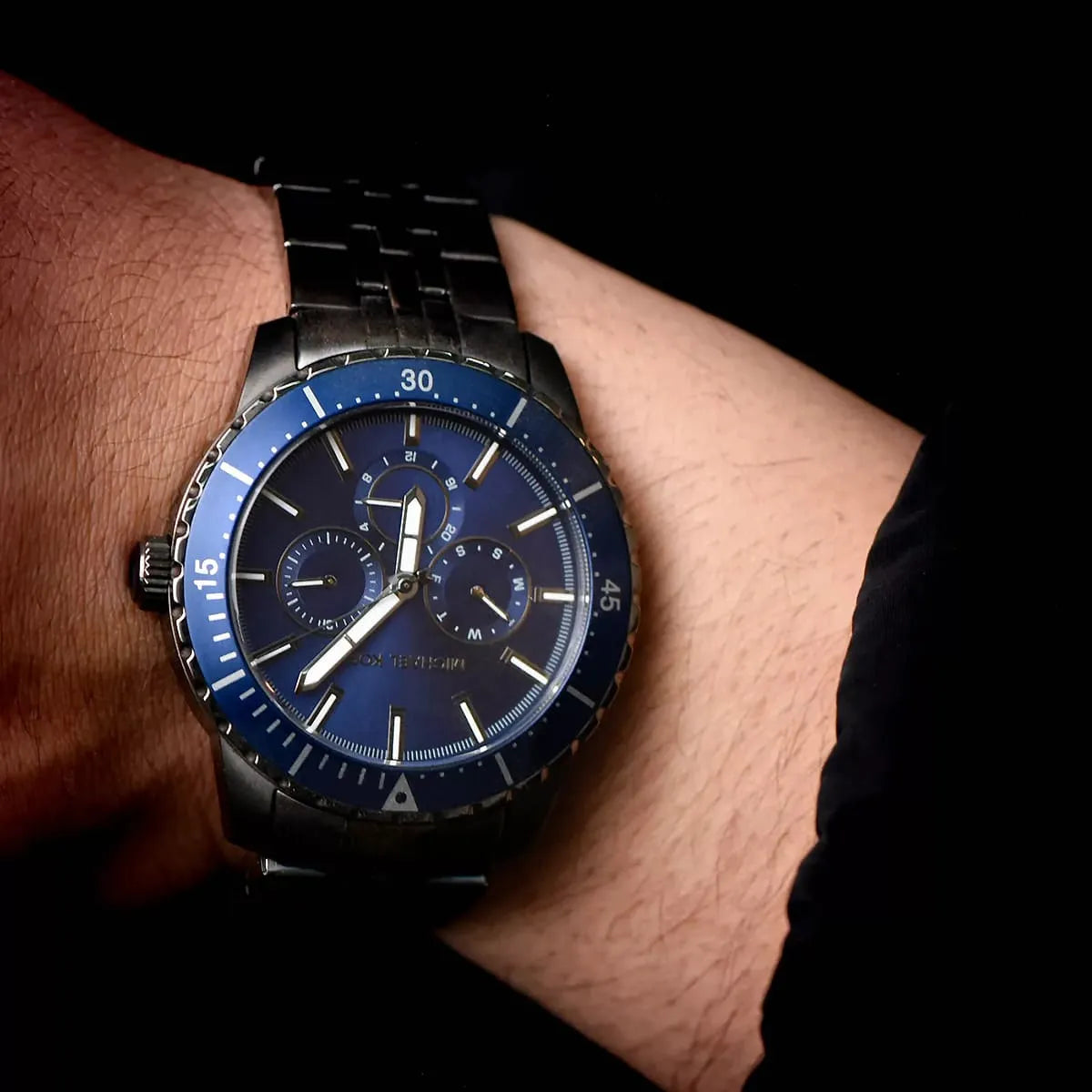 Michael Kors Cunningham MK7155 chronograph watch worn on wrist showing blue dial with subdials and gunmetal bracelet