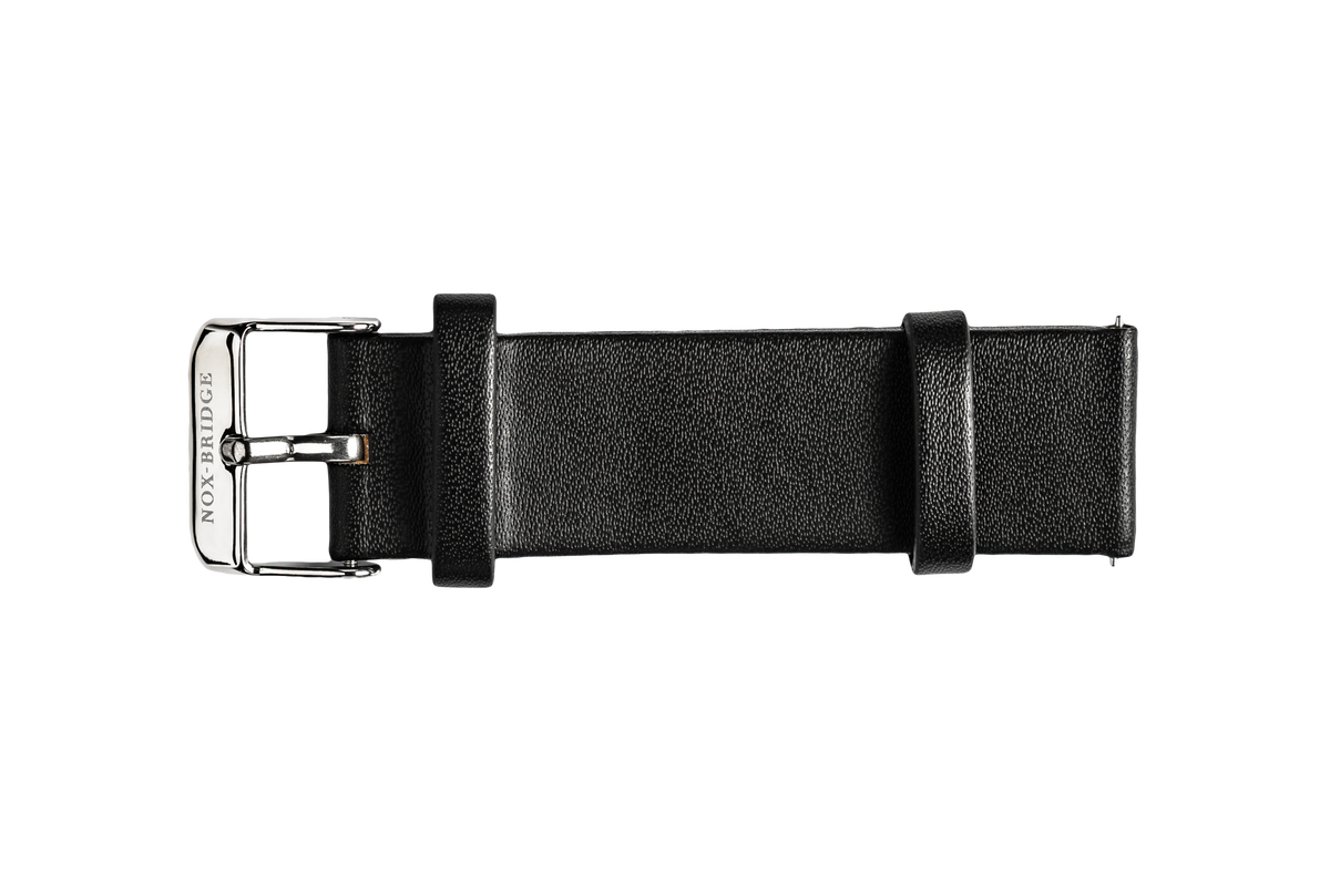 Black vegan leather watch strap with metal buckle, laid flat