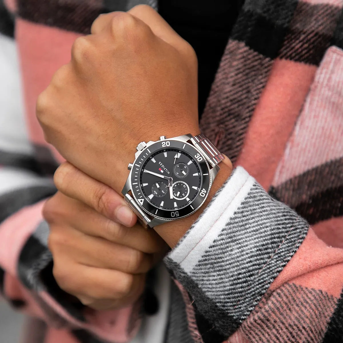 Larson watch worn on wrist with plaid shirt sleeve, showing black dial and steel bracelet