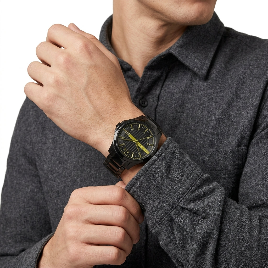 A close-up of a man wearing a dark gray heathered long-sleeve shirt and adjusting his cuff while wearing a black watch with a black strap and a bright yellow dial.