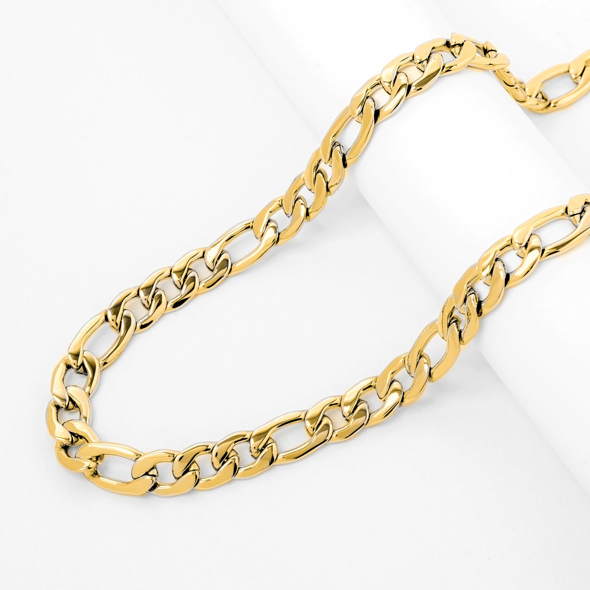 Gold figaro chain displayed on white surface showing chain length and link pattern