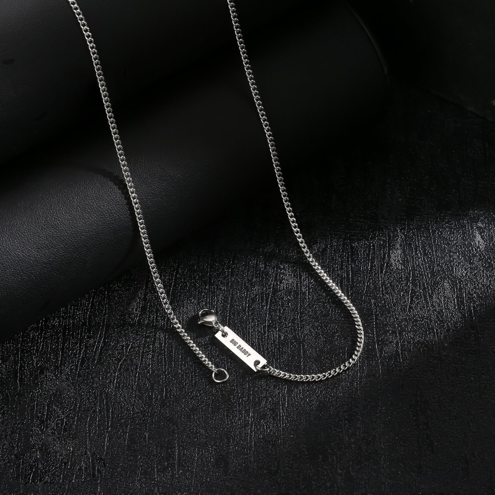 Close-up of Big Daddy silver Cuban chain links and engraved rectangular plate detail