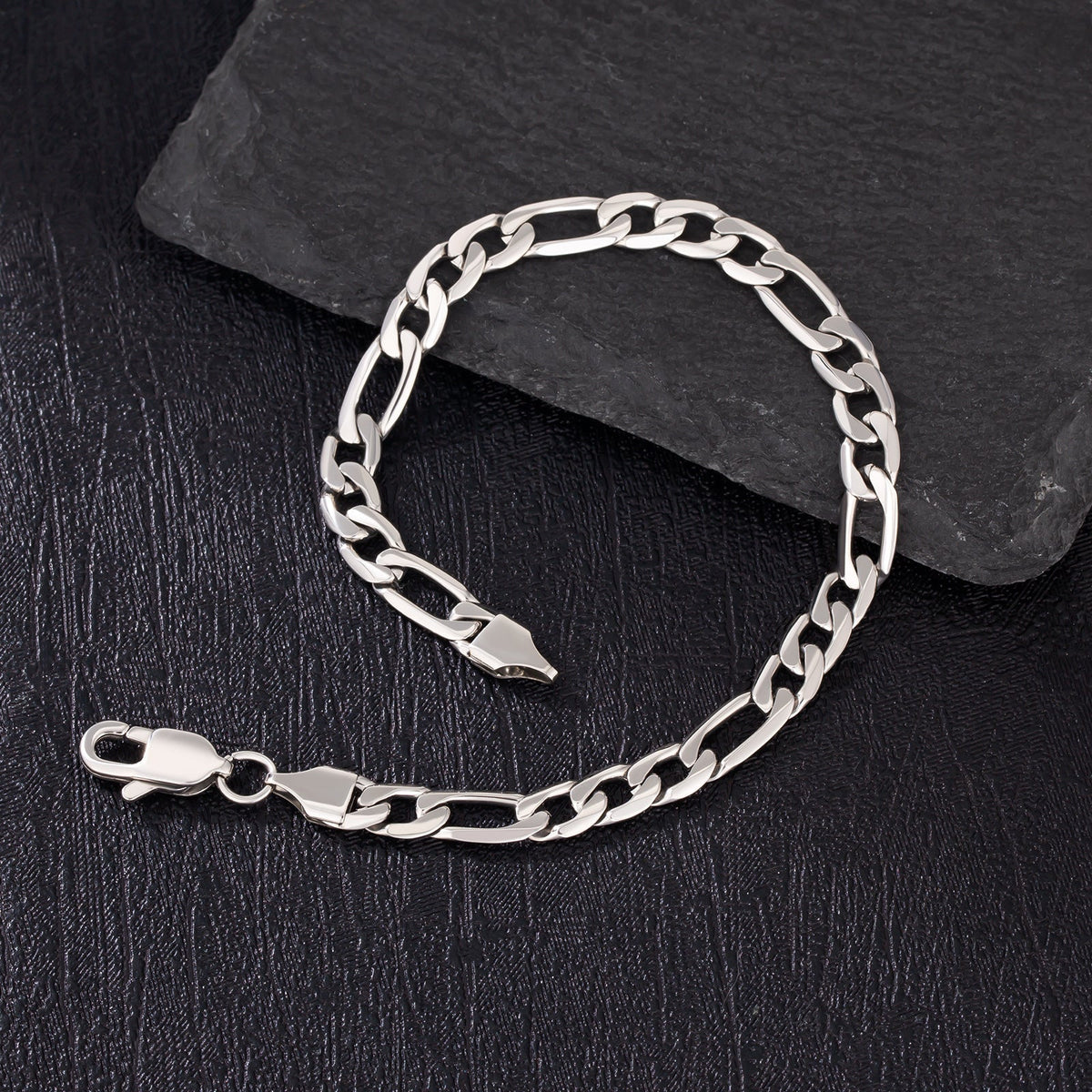 6mm steel figaro silver bracelet detail on dark slate surface with clasp visible