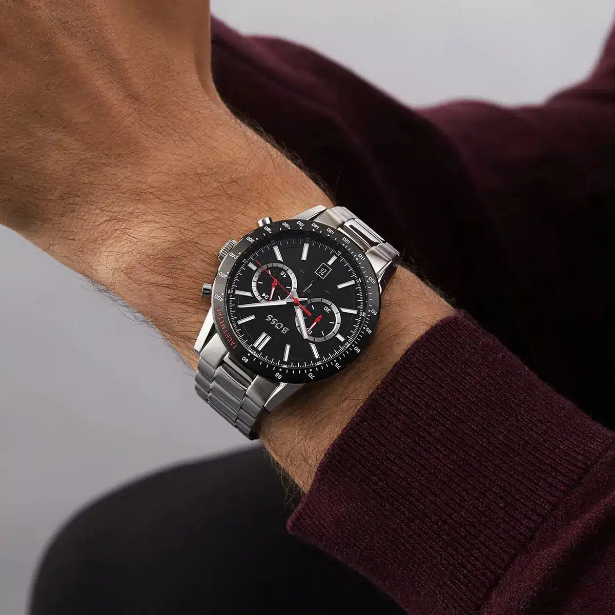 Hugo Boss Allure watch on wrist with maroon sweater showing chronograph dial and steel bracelet