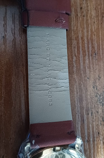 Watch strap interior side showing white fabric with embossed branding and adjustment holes