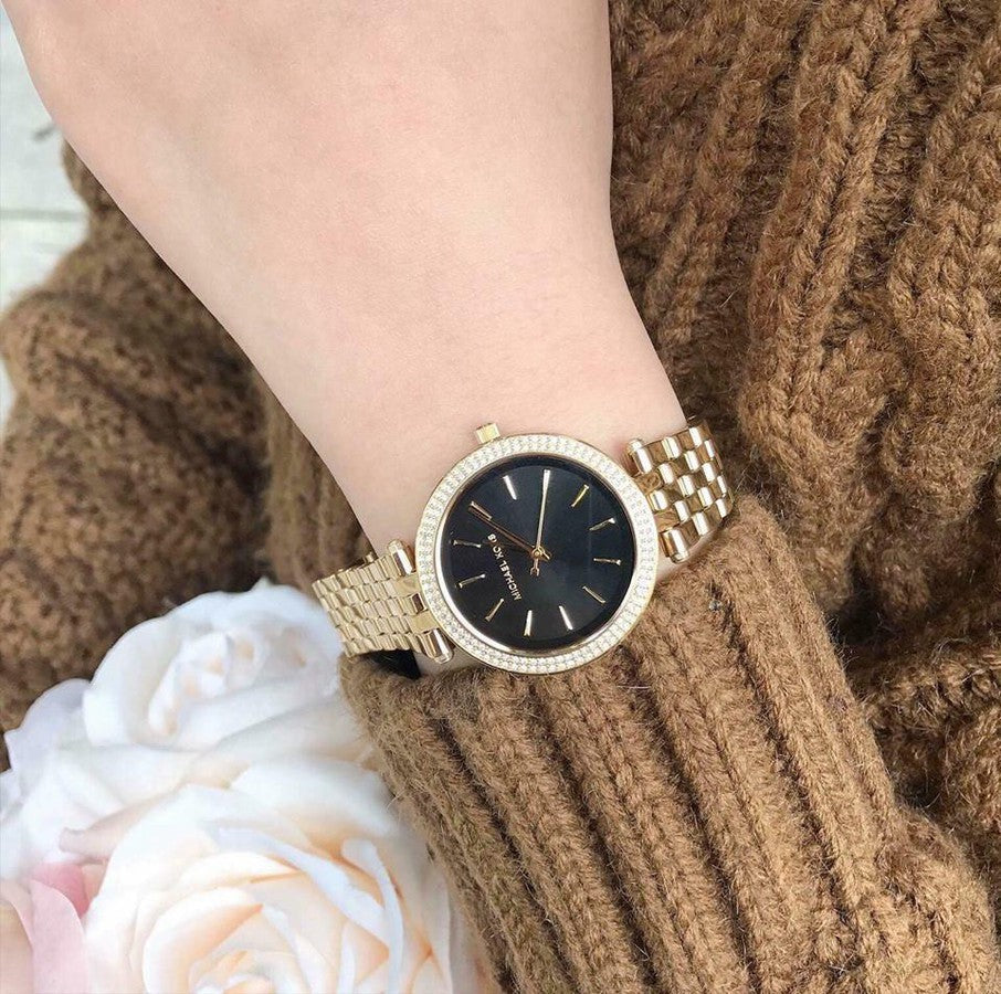 Michael Kors Darci gold watch on wrist showing black dial and crystal bezel
