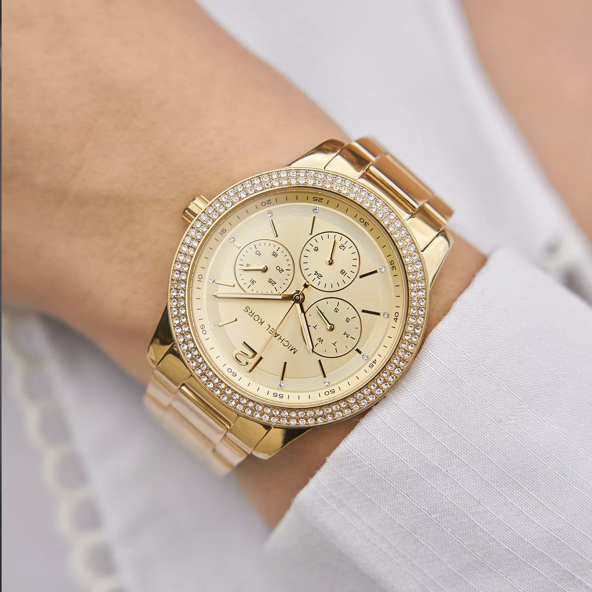 Michael Kors Oversized Tibby gold chronograph watch worn on wrist with crystal bezel detail
