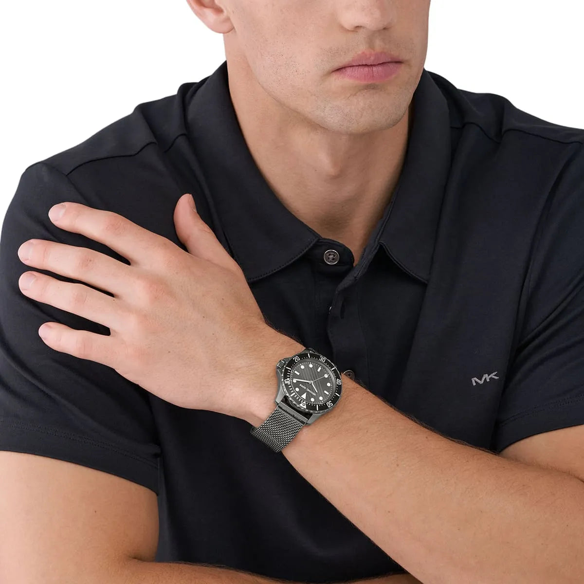 Michael Kors Everest gunmetal watch worn on man's wrist with black polo